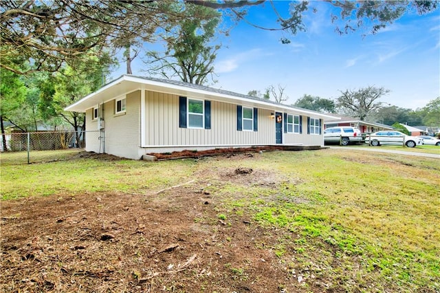 ranch-style house featuring fence, a front lawn, and brick siding