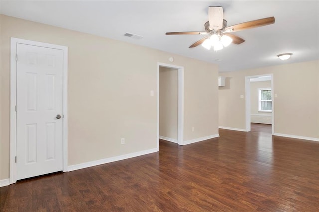 empty room featuring dark wood-type flooring, visible vents, and baseboards