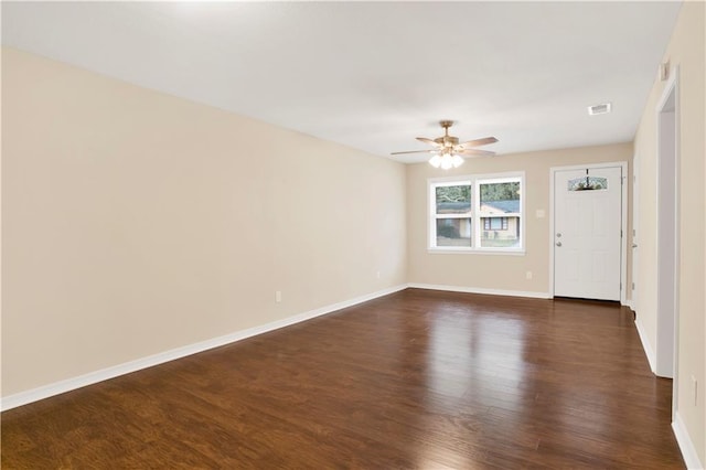 spare room featuring visible vents, dark wood finished floors, baseboards, and ceiling fan