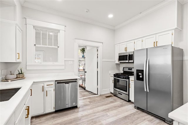 kitchen featuring stainless steel appliances, light hardwood / wood-style floors, ornamental molding, and white cabinets