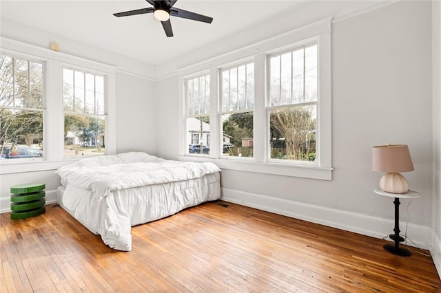 bedroom featuring ceiling fan, multiple windows, and wood-type flooring