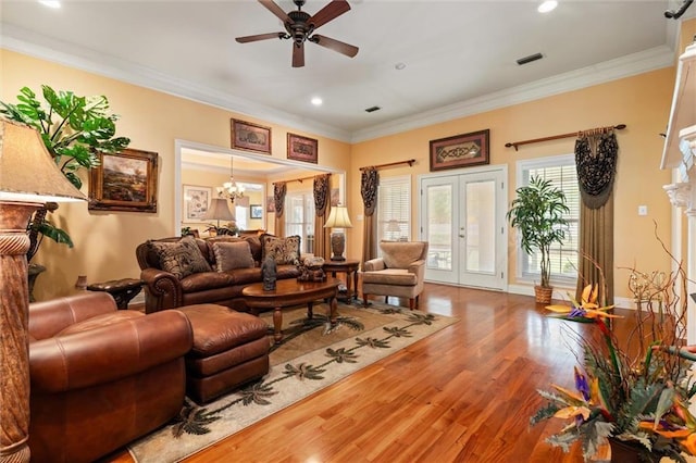 living area with wood finished floors, crown molding, and french doors