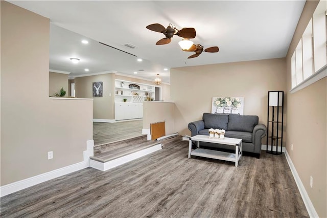 living room with wood-type flooring, ornamental molding, and ceiling fan