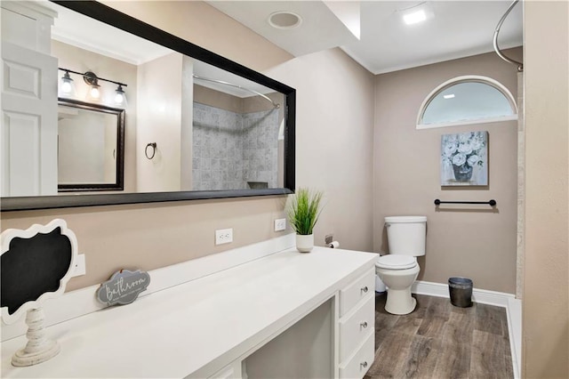 bathroom featuring wood-type flooring, walk in shower, vanity, and toilet