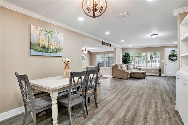 dining space featuring crown molding, hardwood / wood-style floors, and a chandelier