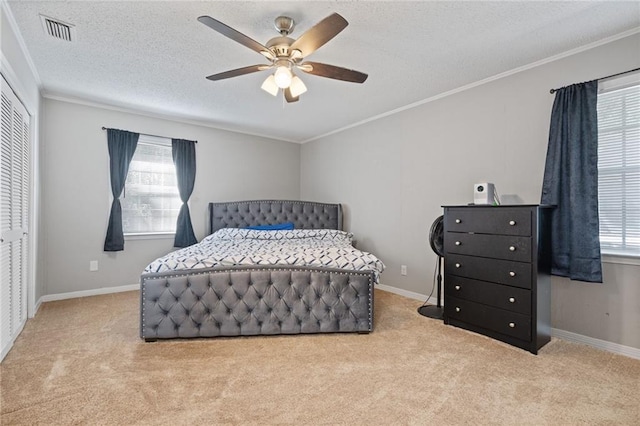 carpeted bedroom featuring ceiling fan, ornamental molding, a textured ceiling, and a closet