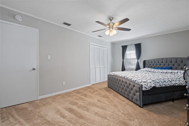 carpeted bedroom featuring a textured ceiling, a closet, ceiling fan, and ornamental molding