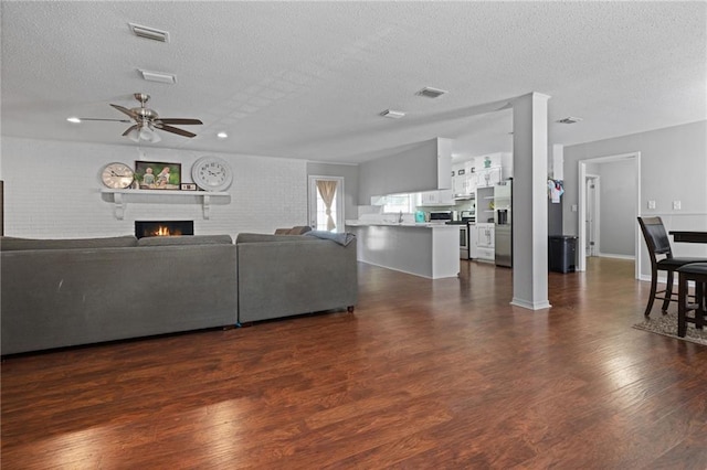 unfurnished living room with a textured ceiling, ceiling fan, dark wood-type flooring, and sink