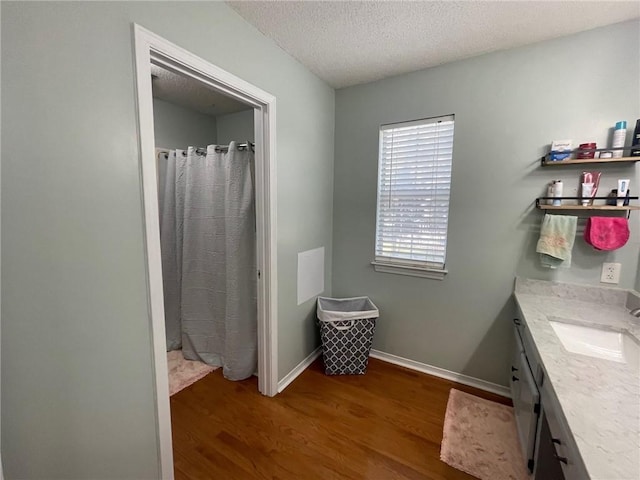 bathroom featuring a shower with curtain, a textured ceiling, wood finished floors, baseboards, and vanity