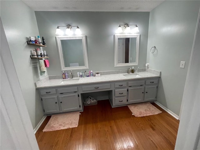 bathroom with hardwood / wood-style floors, double vanity, baseboards, and a sink