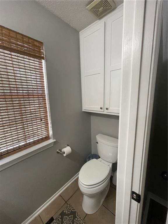 bathroom with visible vents, toilet, a textured ceiling, tile patterned flooring, and baseboards