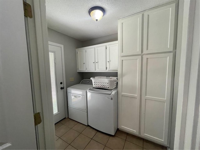 clothes washing area featuring light tile patterned flooring, independent washer and dryer, a textured ceiling, and cabinet space