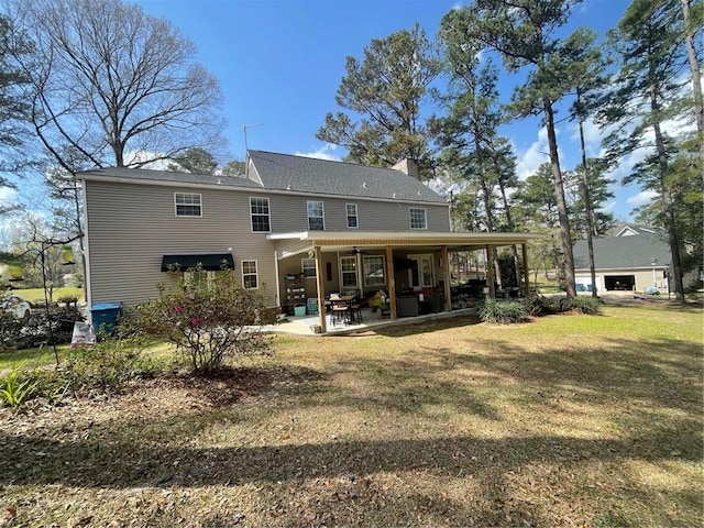 rear view of property featuring a patio, a lawn, and a chimney