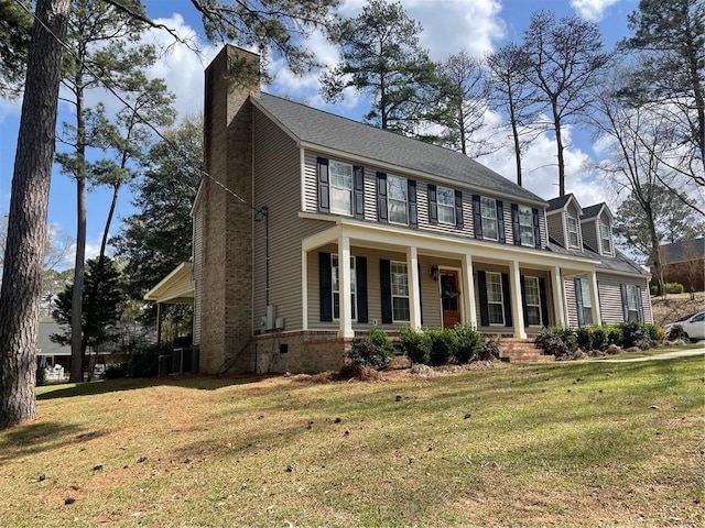 colonial home featuring a front lawn, covered porch, and a chimney