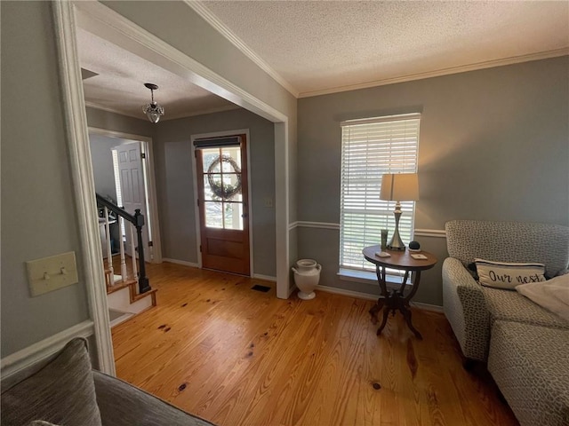 entrance foyer featuring stairway, wood finished floors, baseboards, a textured ceiling, and crown molding