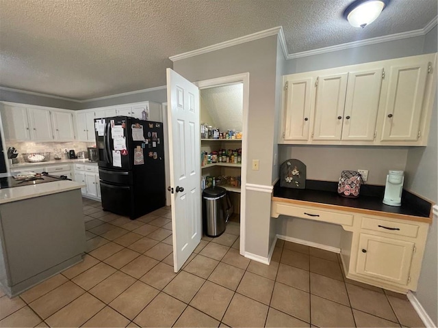 kitchen featuring light tile patterned flooring, white cabinets, crown molding, black refrigerator with ice dispenser, and built in study area