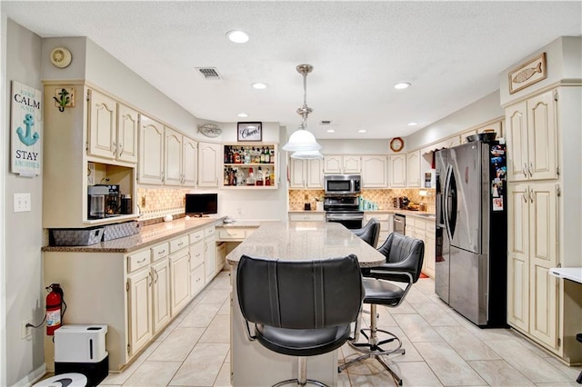 8717 Louis Poiroux Rd N, Theodore, AL 36582 - kitchen with appliances with stainless steel finishes, cream cabinetry, a kitchen island, backsplash, and recessed lighting