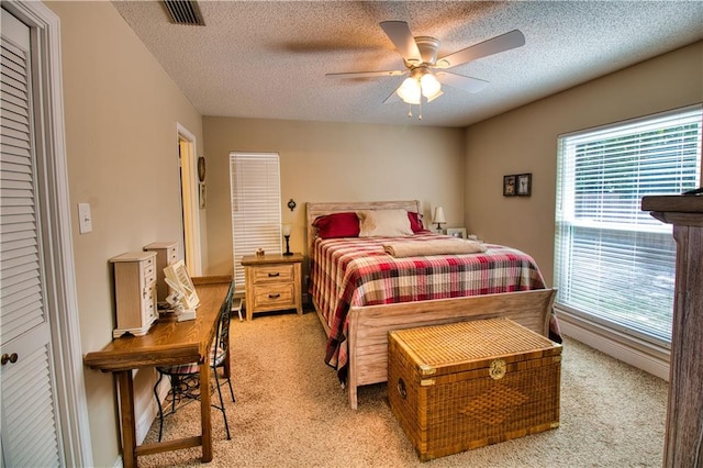 bedroom with light carpet, a textured ceiling, and ceiling fan