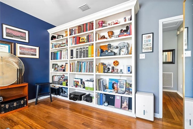 living area with baseboards, visible vents, and wood finished floors