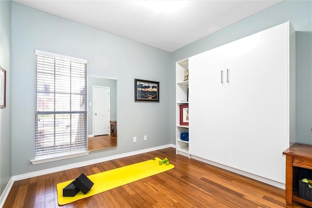 exercise area featuring wood finished floors and baseboards