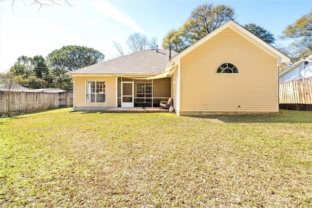 rear view of property with a lawn, fence, and a sunroom