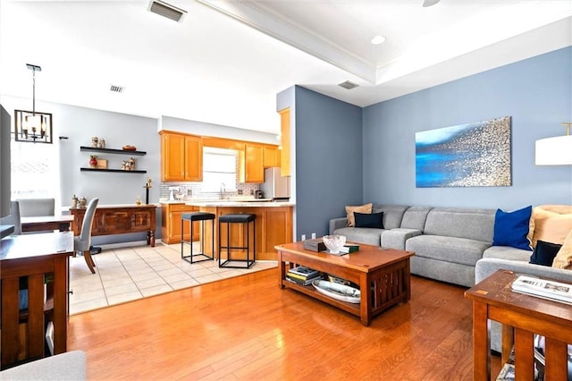 living area featuring a notable chandelier, visible vents, and light wood-style floors