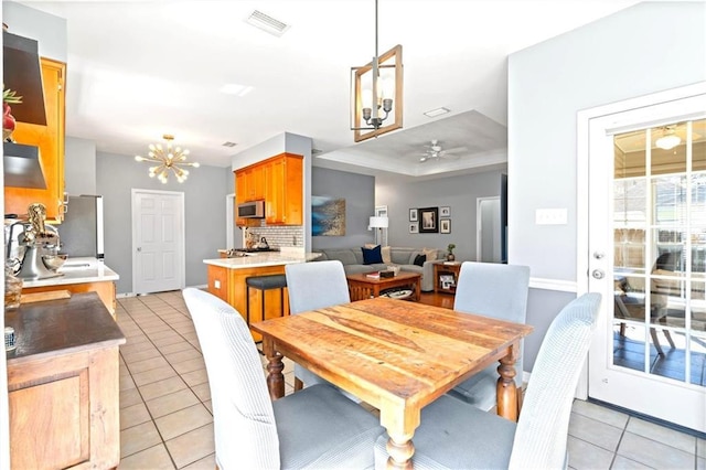 dining room featuring light tile patterned flooring, visible vents, and ceiling fan with notable chandelier