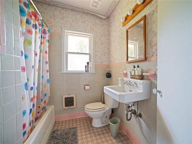 full bathroom featuring toilet, shower / bath combination with curtain, tile walls, heating unit, and sink