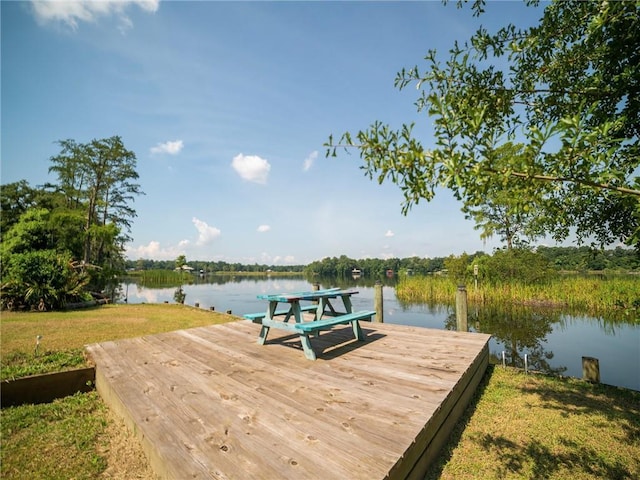 view of dock with a water view and a lawn