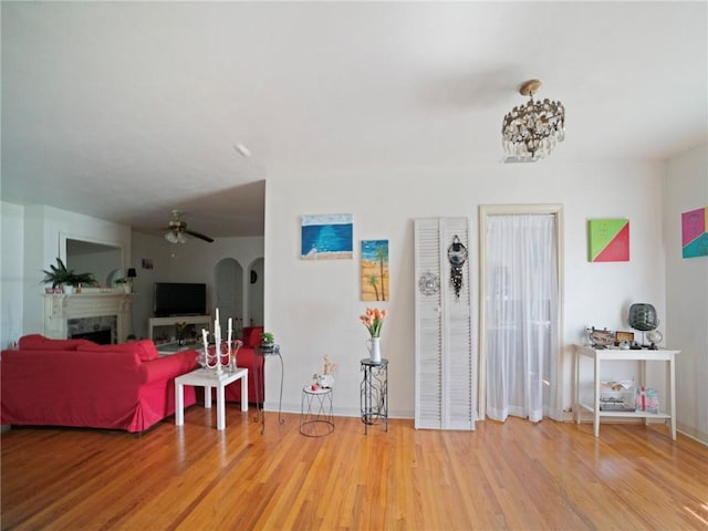 living room featuring ceiling fan with notable chandelier and hardwood / wood-style flooring