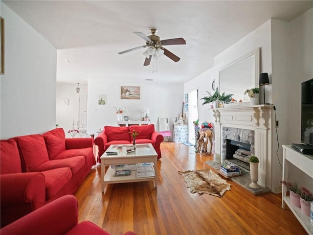 living room with a fireplace, ceiling fan, and light hardwood / wood-style flooring