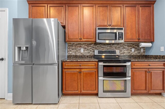 kitchen with dark stone counters, backsplash, light tile patterned floors, and stainless steel appliances