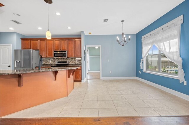 kitchen featuring a kitchen breakfast bar, light tile patterned flooring, stone countertops, stainless steel appliances, and decorative light fixtures