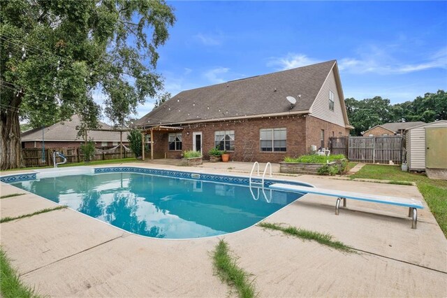 view of swimming pool featuring a patio, a diving board, and a storage unit