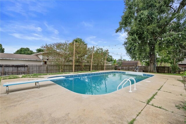 view of swimming pool with a diving board and a patio