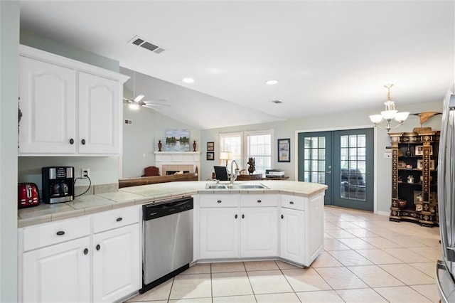 kitchen with appliances with stainless steel finishes, tile counters, white cabinets, and kitchen peninsula