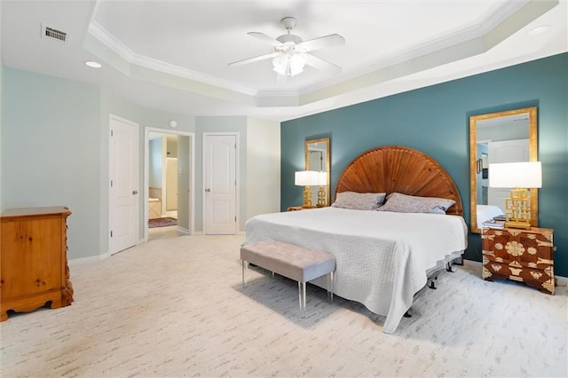 carpeted bedroom with crown molding, ensuite bath, a raised ceiling, and ceiling fan