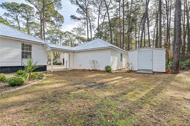 back of house featuring a storage shed, a lawn, and a carport