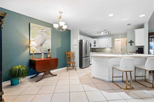 kitchen featuring sink, stainless steel fridge, white cabinetry, decorative backsplash, and kitchen peninsula