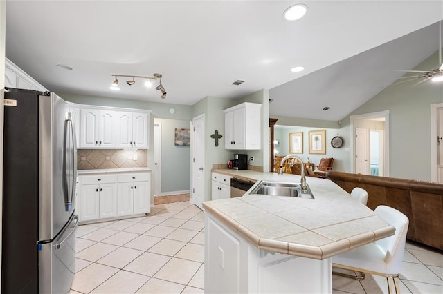 kitchen featuring appliances with stainless steel finishes, white cabinetry, sink, tile counters, and kitchen peninsula