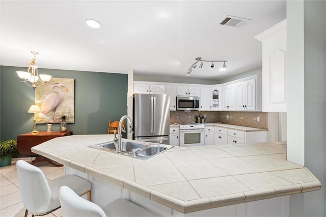 kitchen featuring appliances with stainless steel finishes, sink, tile counters, and kitchen peninsula