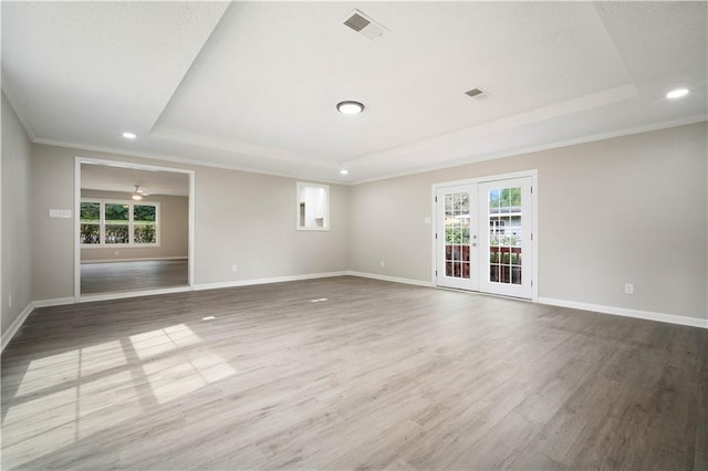 unfurnished room featuring french doors, a tray ceiling, wood finished floors, and visible vents