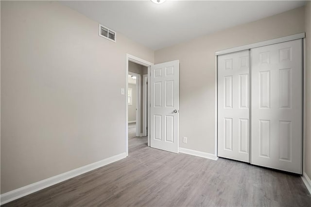 unfurnished bedroom with visible vents, baseboards, and wood finished floors