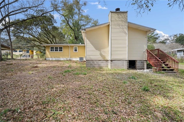 view of side of home with cooling unit, fence, and a chimney