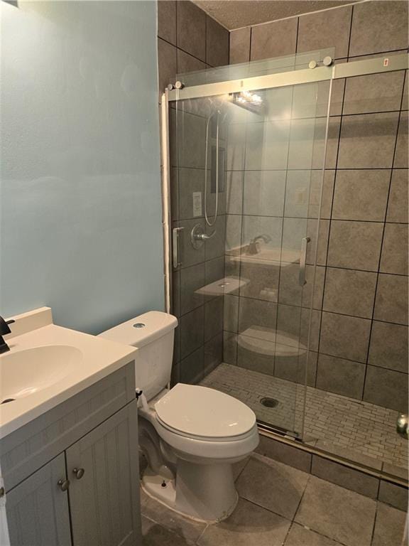 bathroom with tile patterned flooring, vanity, toilet, and a shower with door