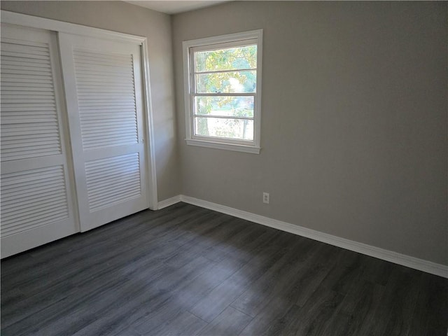 unfurnished bedroom featuring a closet and dark wood-type flooring