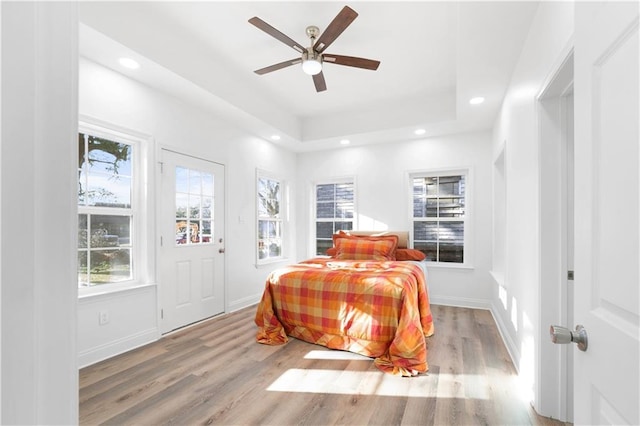 bedroom featuring a raised ceiling, ceiling fan, and light hardwood / wood-style floors