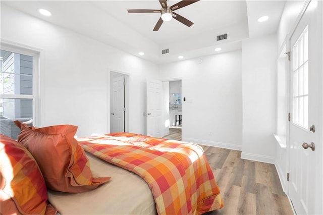 bedroom featuring hardwood / wood-style flooring, ceiling fan, and a tray ceiling