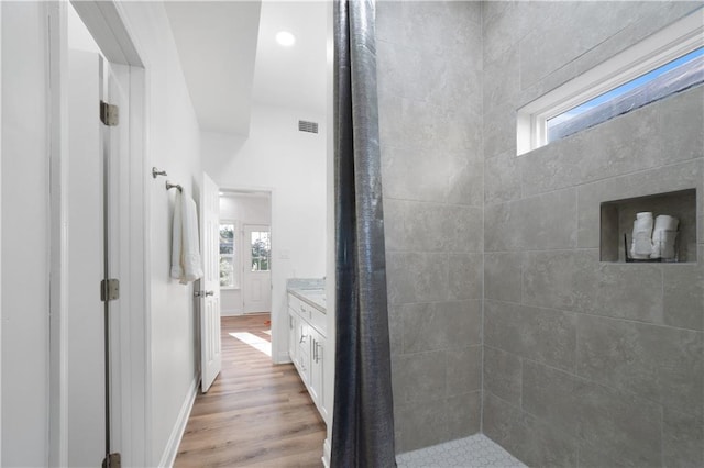 bathroom featuring hardwood / wood-style flooring, vanity, and a tile shower