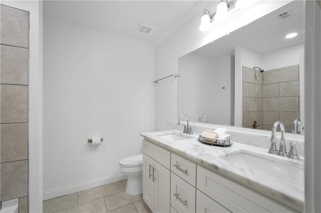 bathroom with tile patterned floors, vanity, a tile shower, and toilet